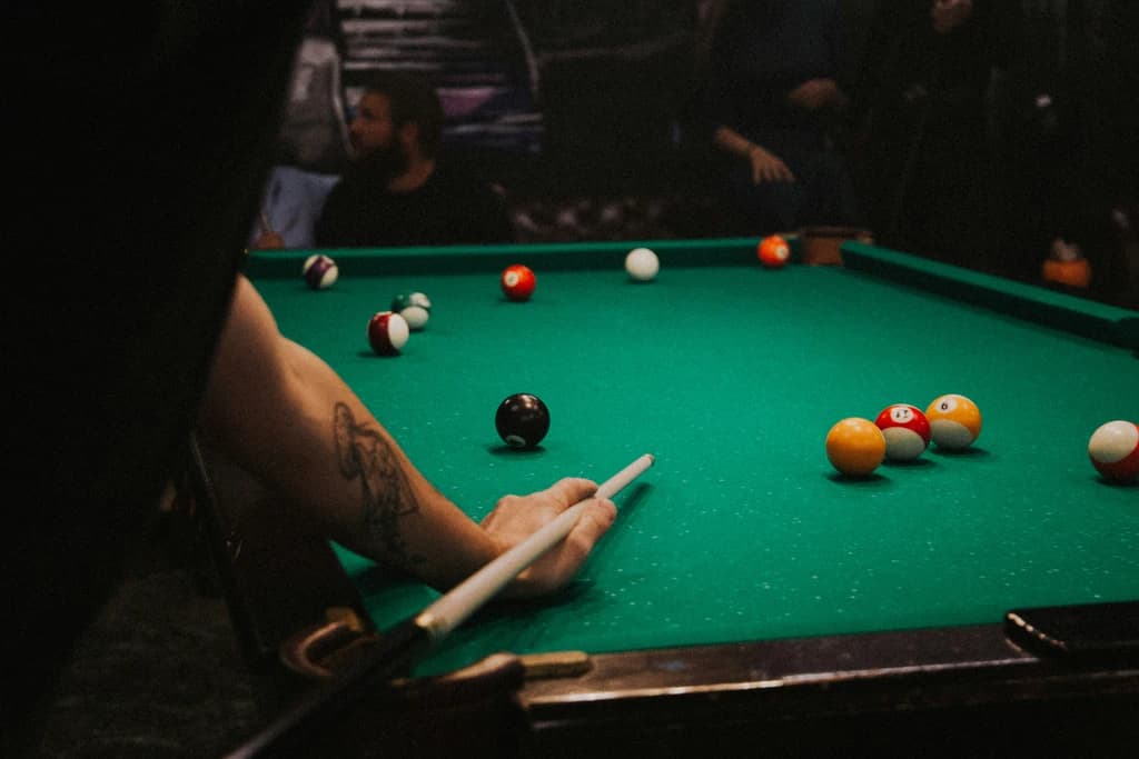 a pool table with someone getting ready to take a shot and holding a pool cue