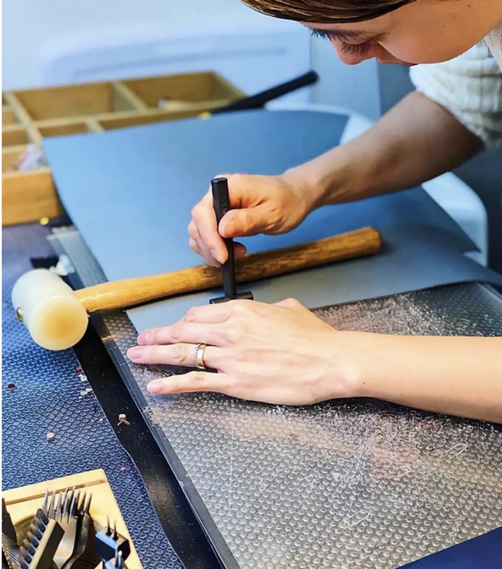 a person with a stamp and hammer making a bracelet