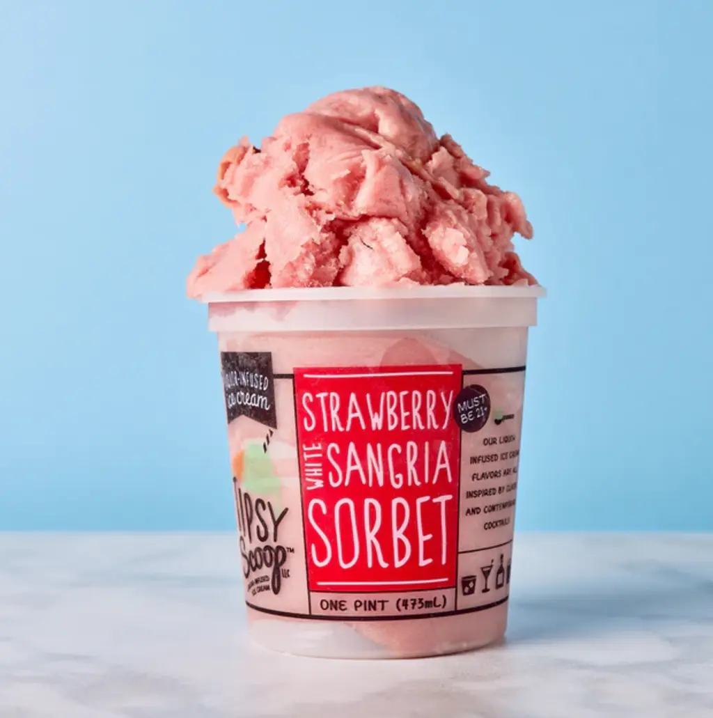 A pint of Strawberry White Sangria Sorbet from Tipsy Scoop, with a scoop of the pink sorbet on top against a blue background.