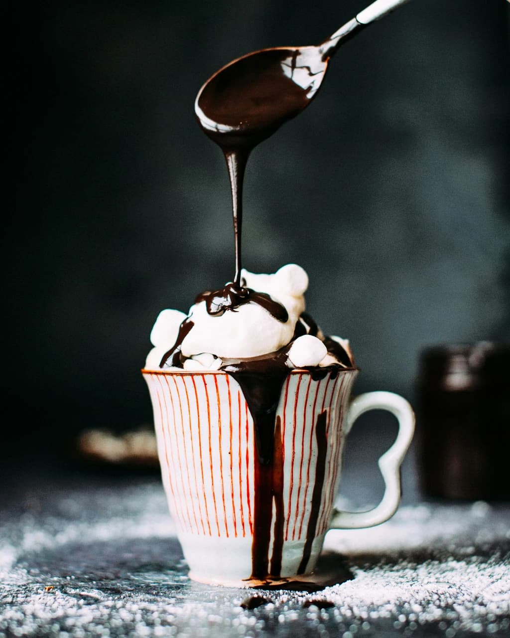 a drink with whip cream on it and chocolate being drizzled on top