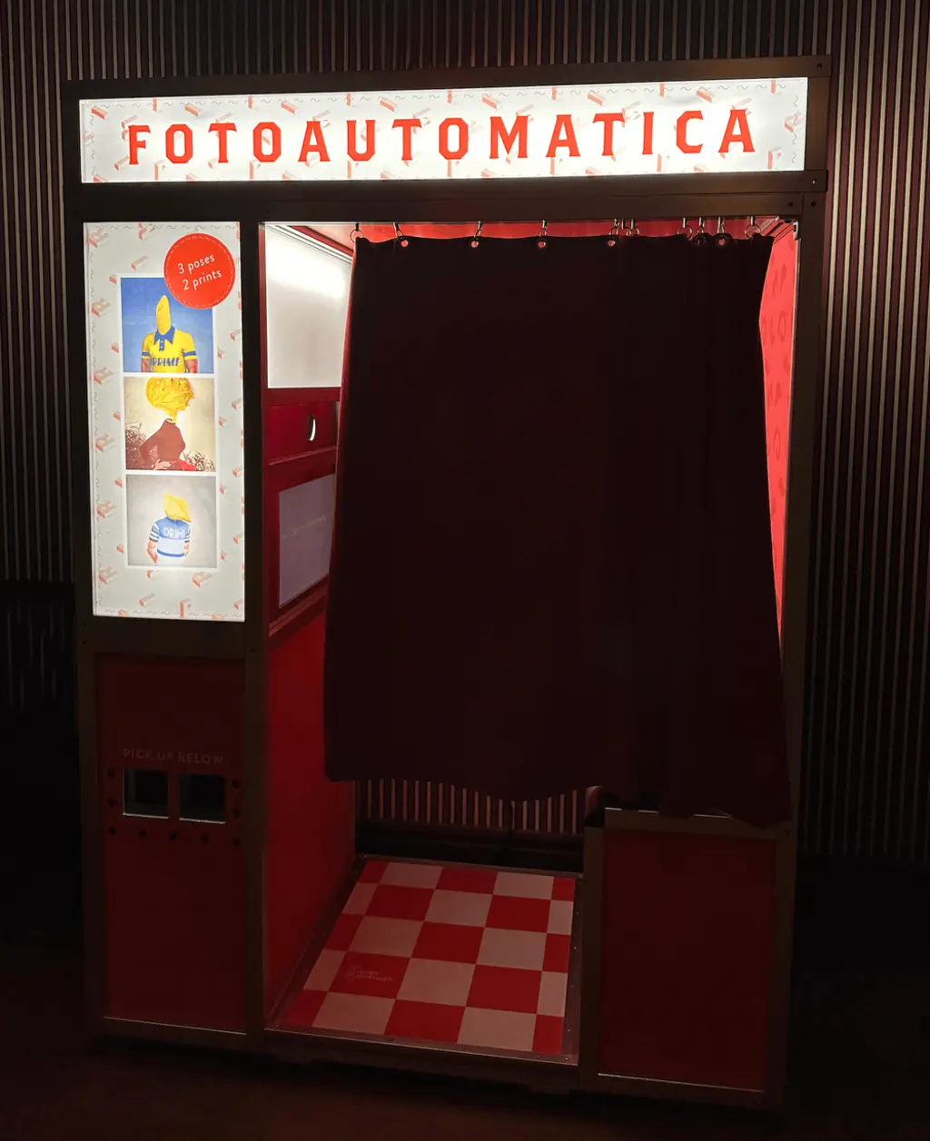 A classic red and white photo booth with a vintage design and checkered floor, branded 'Fotoautomatica.'